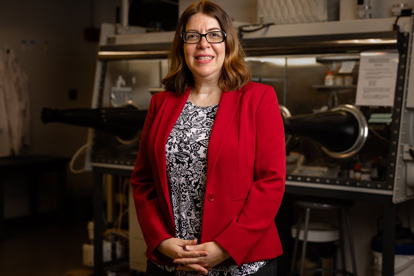Portrait of Haleh Ardebili. She is wearing a red blazer i=with a white and black blouse underneath.  