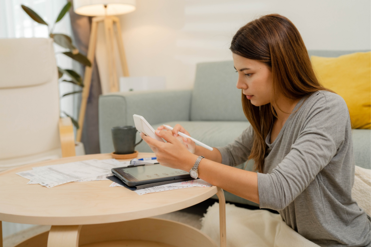 A woman sitting at a table using a stylus.