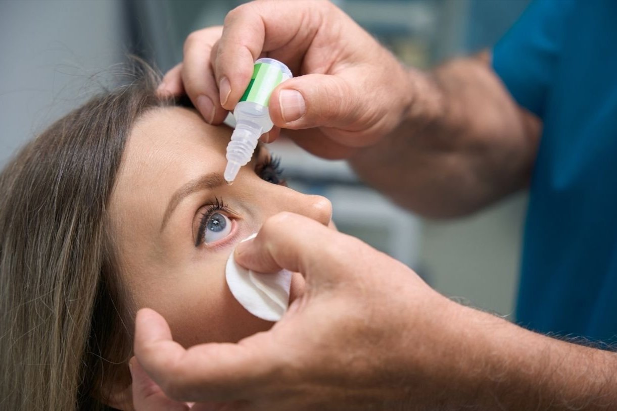 A person using a dropper to remove the eye drops.