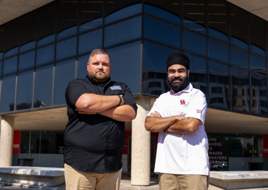 Image of alumnus Shawn Singh (’18) and Darren Randle (’12) posing together outside of C. T. Bauer College of Business.